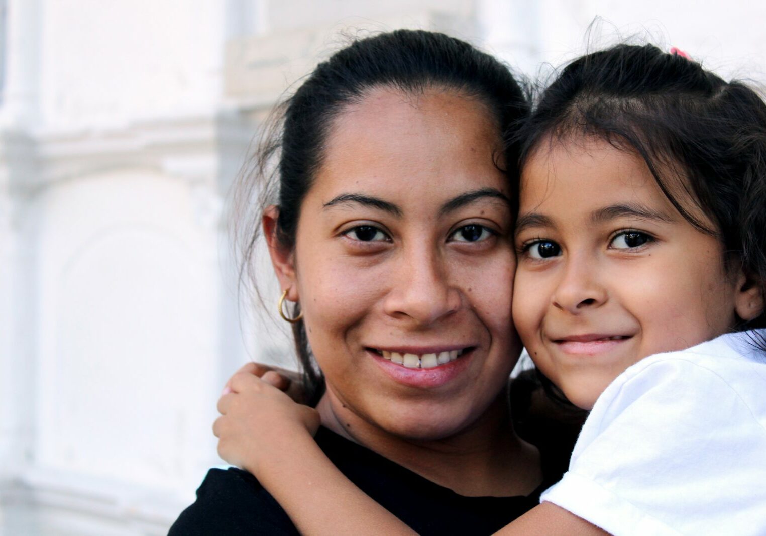 Woman holding child and both smiling towards camera